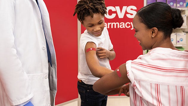Mother and child showing each other their bandages after receiving vaccination at CVS pharmacy