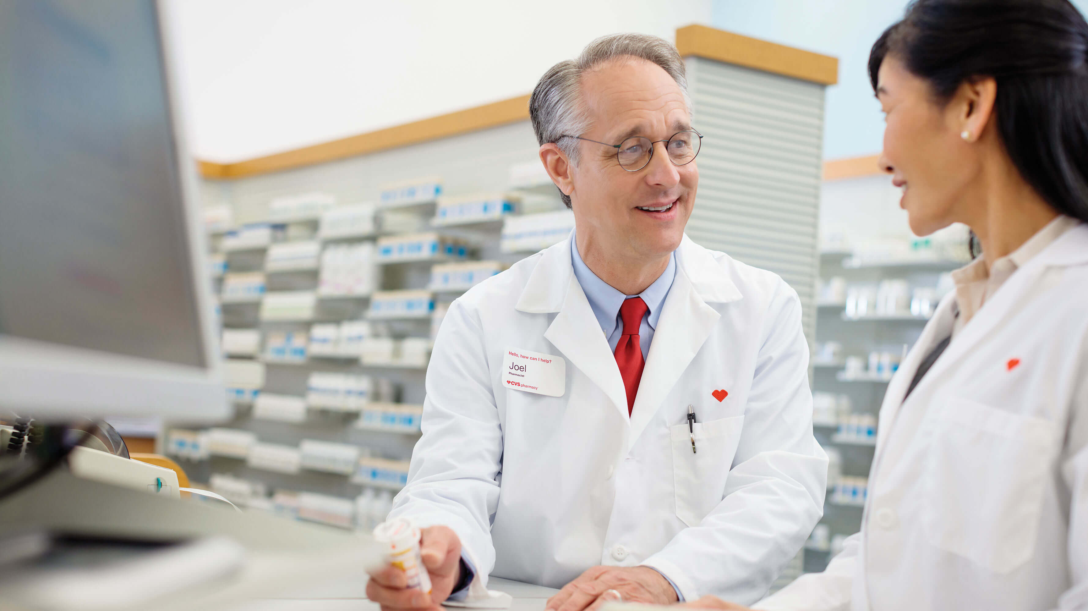 A senior pharmacist coaching an employee behind the counter at a CVS Pharmacy location.