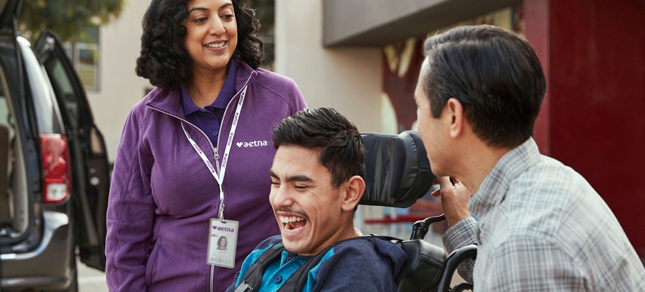 Parents and son in a wheelchair outside smiling