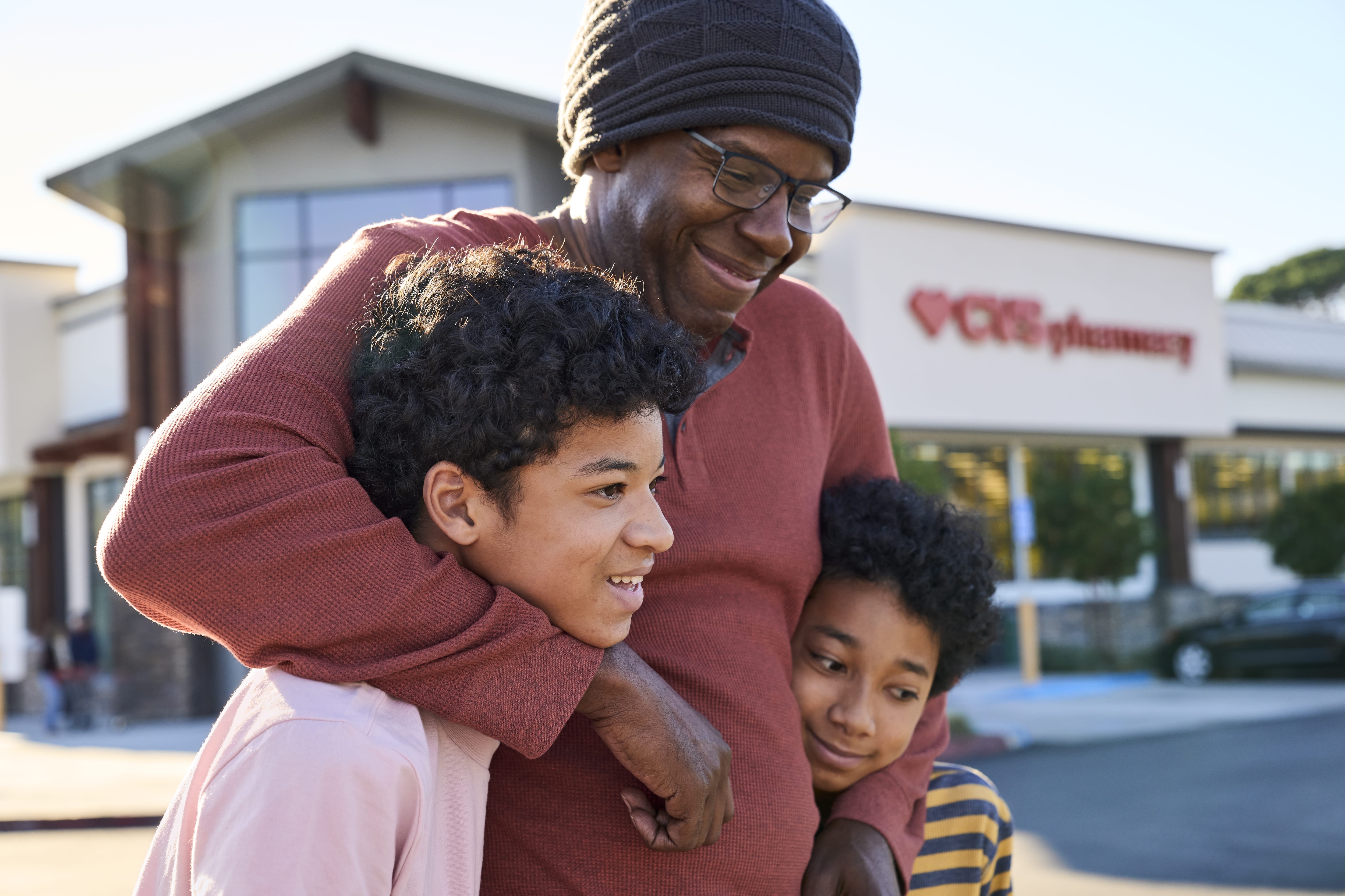 A man with his children in front of a CVS Pharmacy