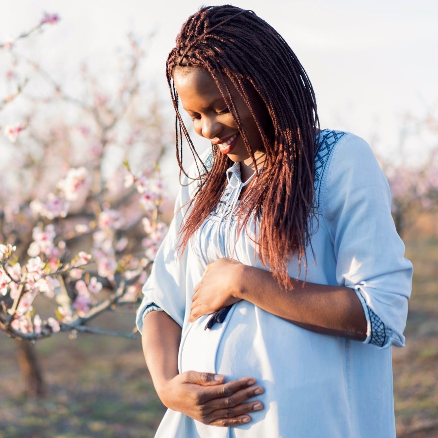 Pregnant women holder her stomach in front of cherry blossoms