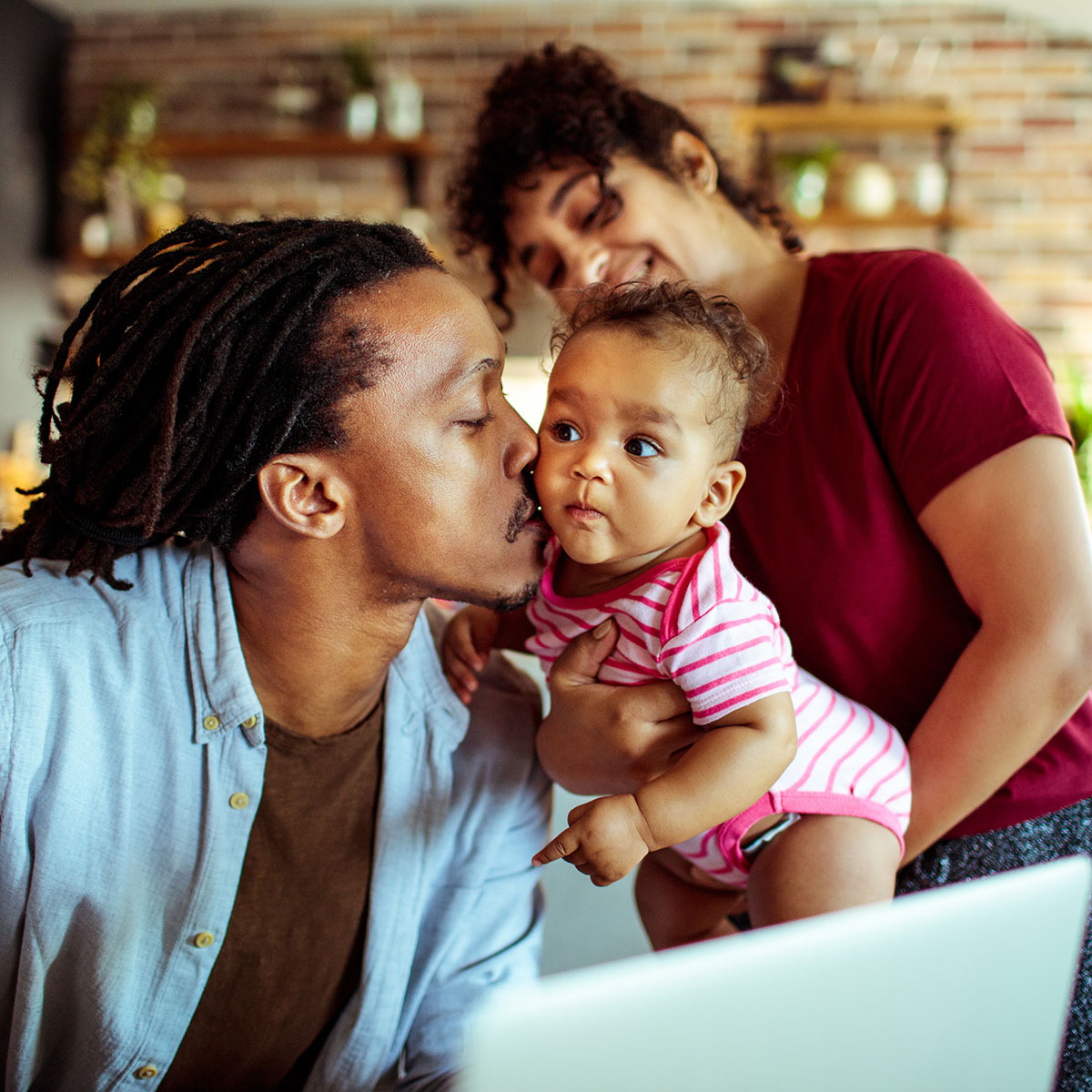 A young family gathers at a laptop for a video call.