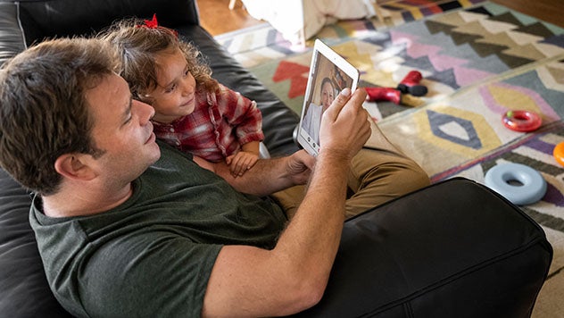 A father sitting on a couch with his young daughter