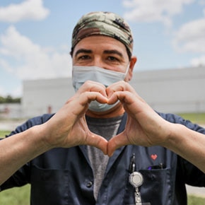 Male in surgical mask making a heart with his hands