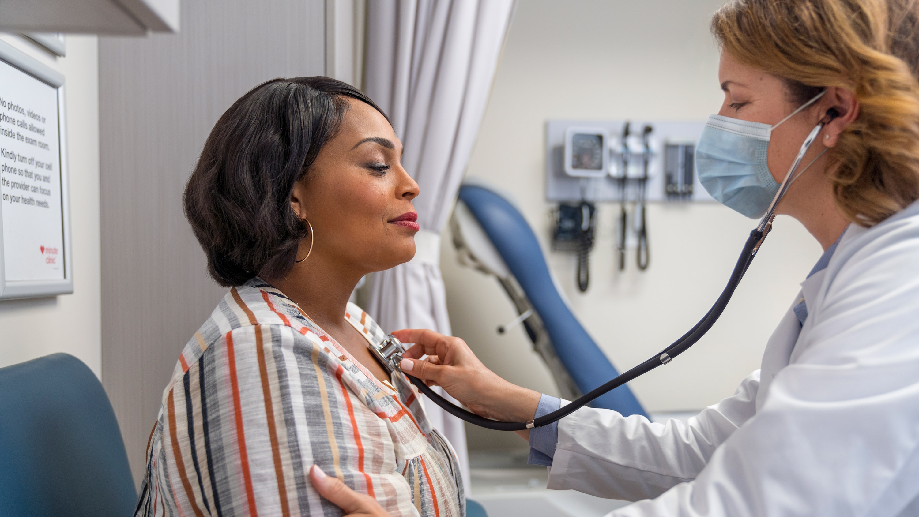 A woman of color gets her heart checked by a MinuteClinic health care provider.