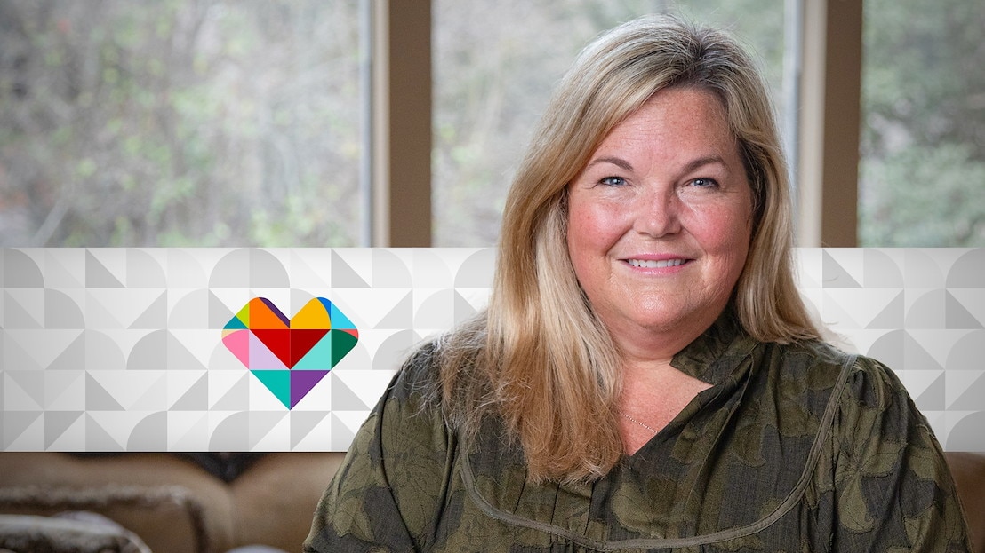 A person sits indoors with a patterned CVS Health heart icon displayed beside them.