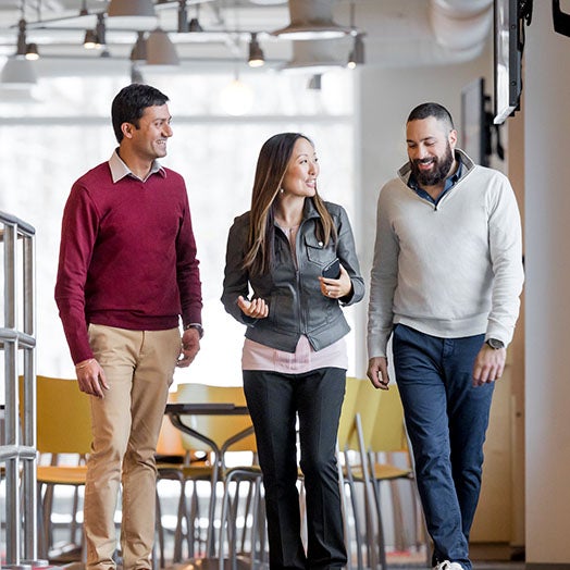 Three people having a conversation while walking through an office