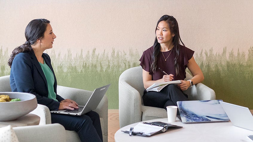 two women sitting in an open office spce having a meeting