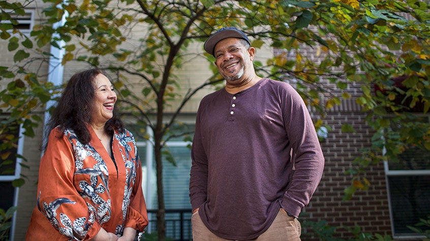 Man and woman smiling in front of a tree