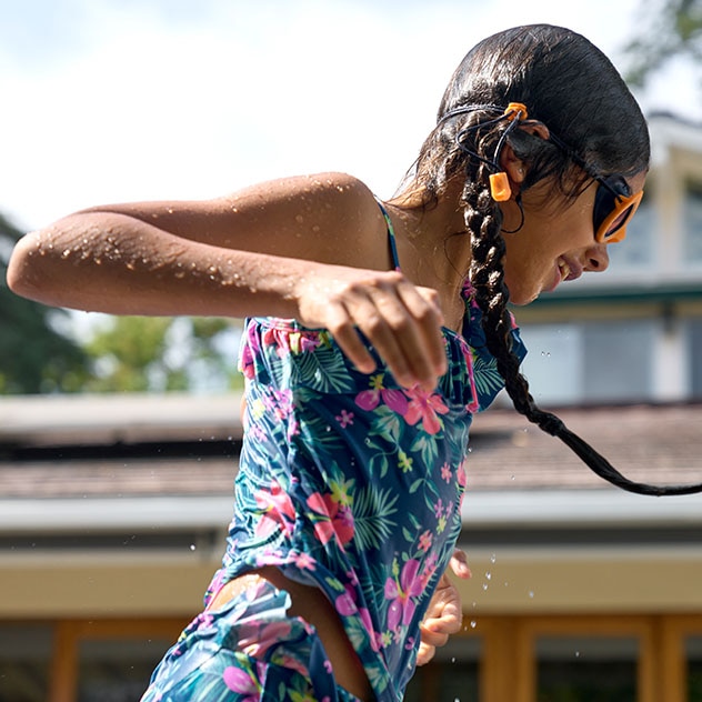 Young girl running through a sprinkler