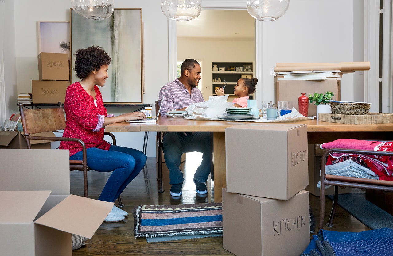 A fmaily sitting around the table with moving boxes around them