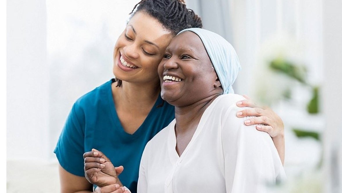 A nurse embracing a patient's shoulder while checking her pulse