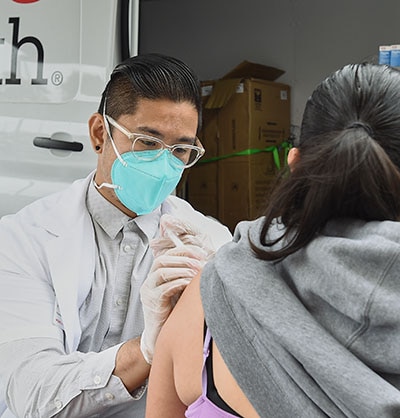 Male medical professional giving a womana shot in her arm