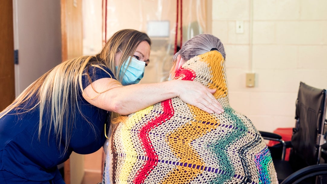 A nurse covering a pateint with a blanket