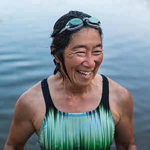 Woman swimming in lake wearing goggles on her head