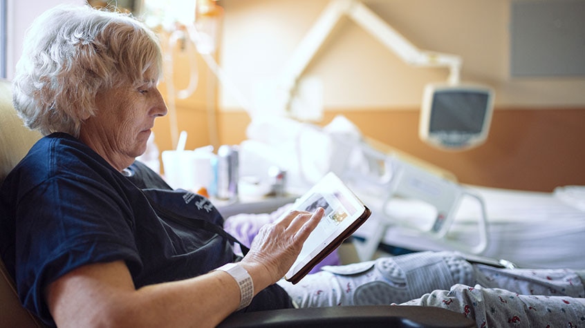 Woman reads book while lying in hospital bed