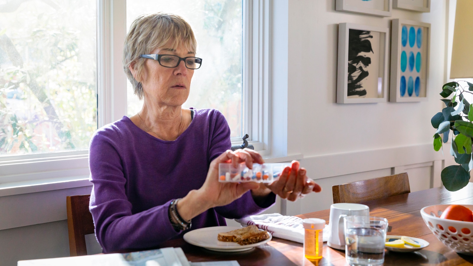 A woman organizes her medication at the breakfast table.