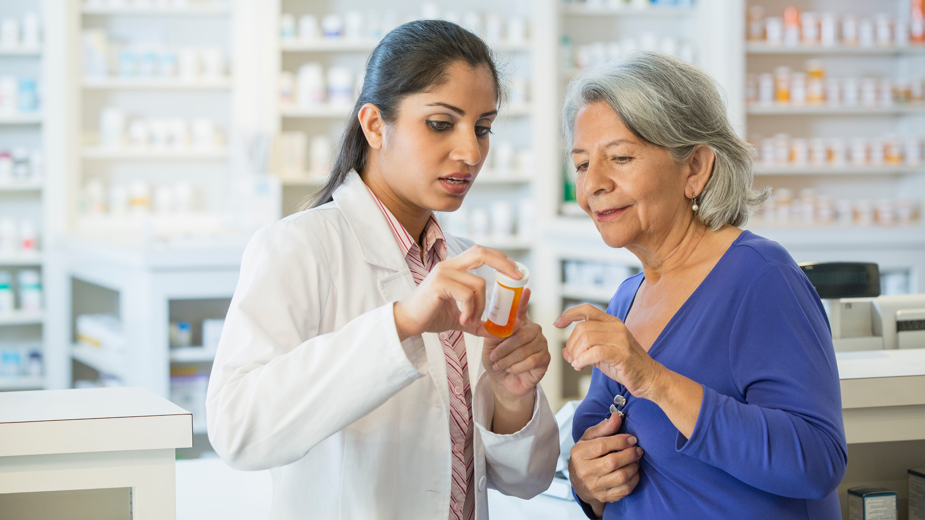 A female pharmacists advises an older female patient about her mediation at the pharmacy counter.