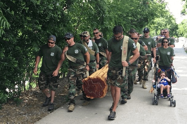 A team of firefighters carries a log to honor their colleagues