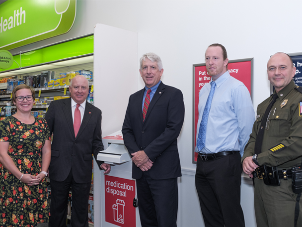 Event attendees pose with a safe medication disposal unit.