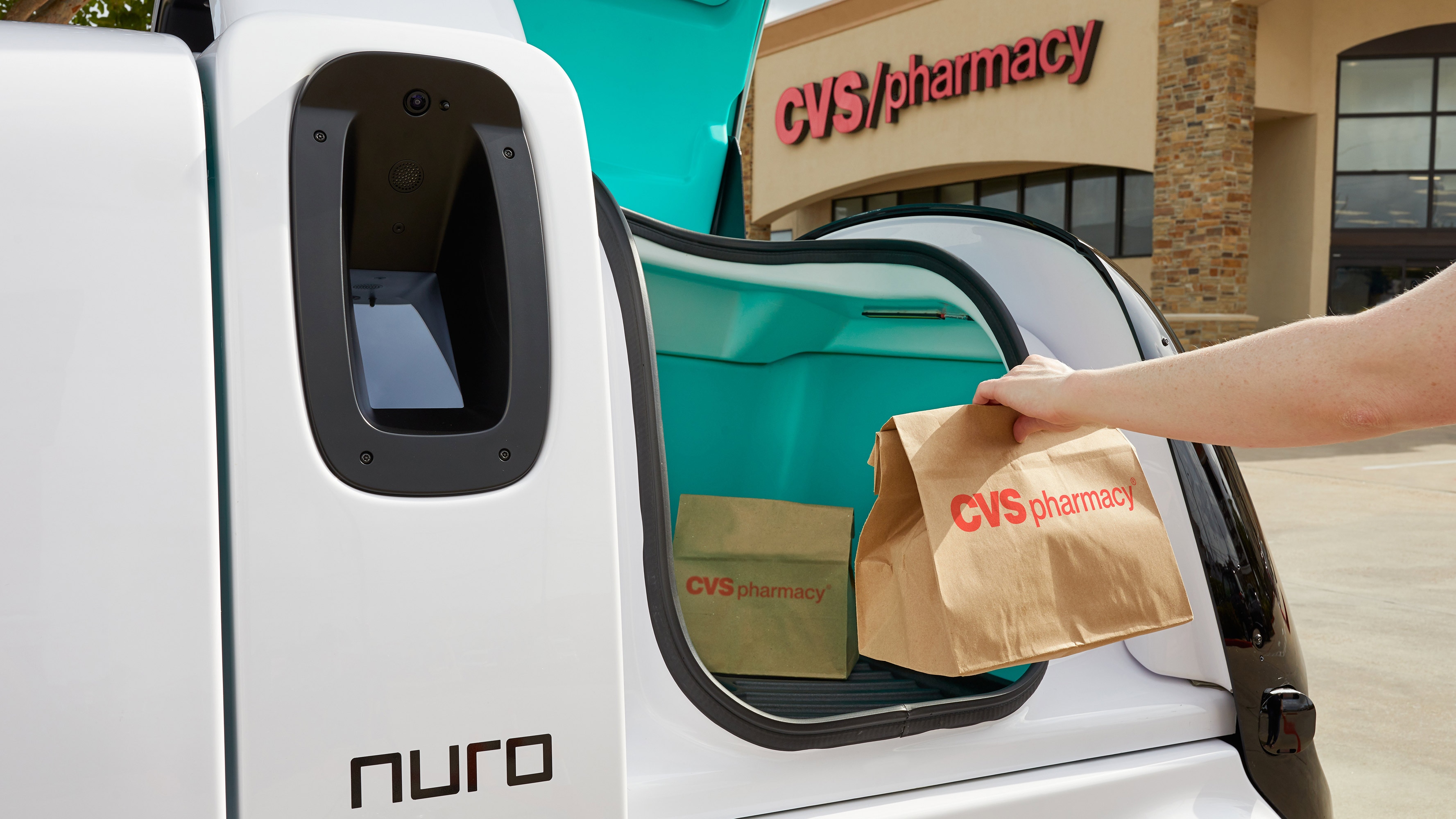 A CVS Pharmacy customer collects a delivery from a Nuro autonomous vehicle outside of a CVS Pharmacy location in Texas.