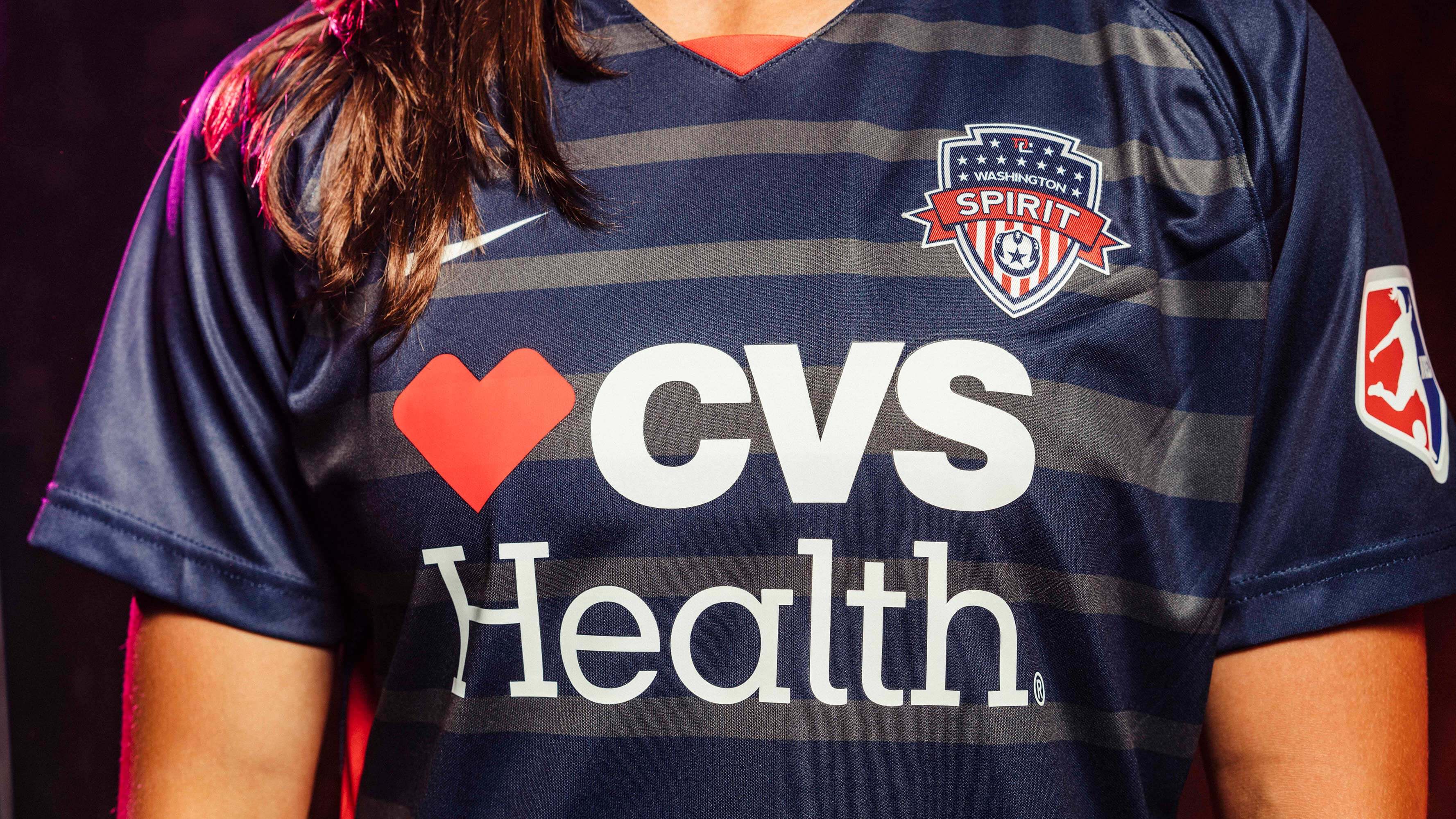 A close up photo of the Washington Spirit (professional soccer team) uniforms, which are dark navy blue and feature CVS Health&#039;s logo on the front under the soccer team&#039;s branding.