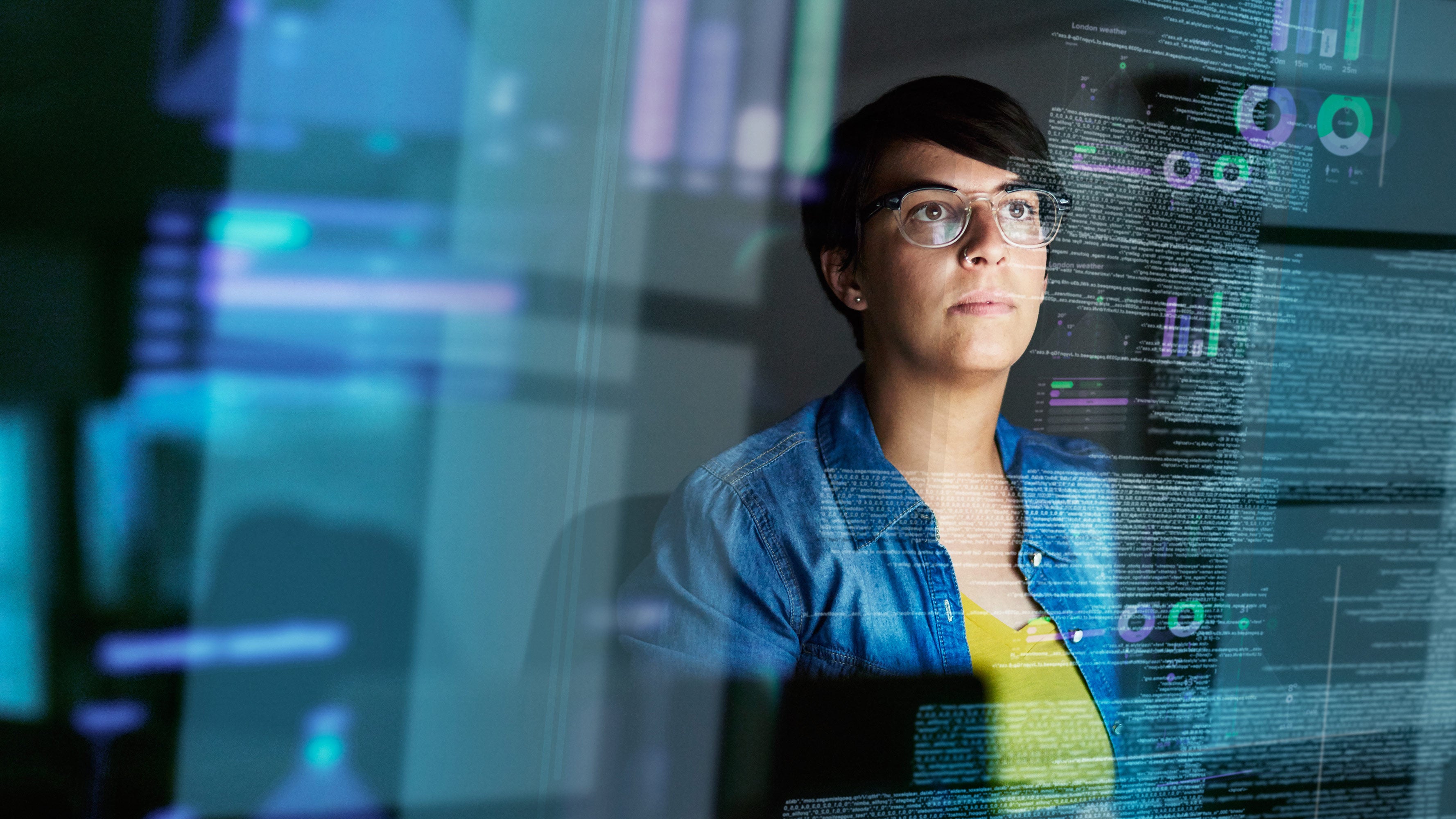 A woman examines a set of data on a very large and reflective computer screen.