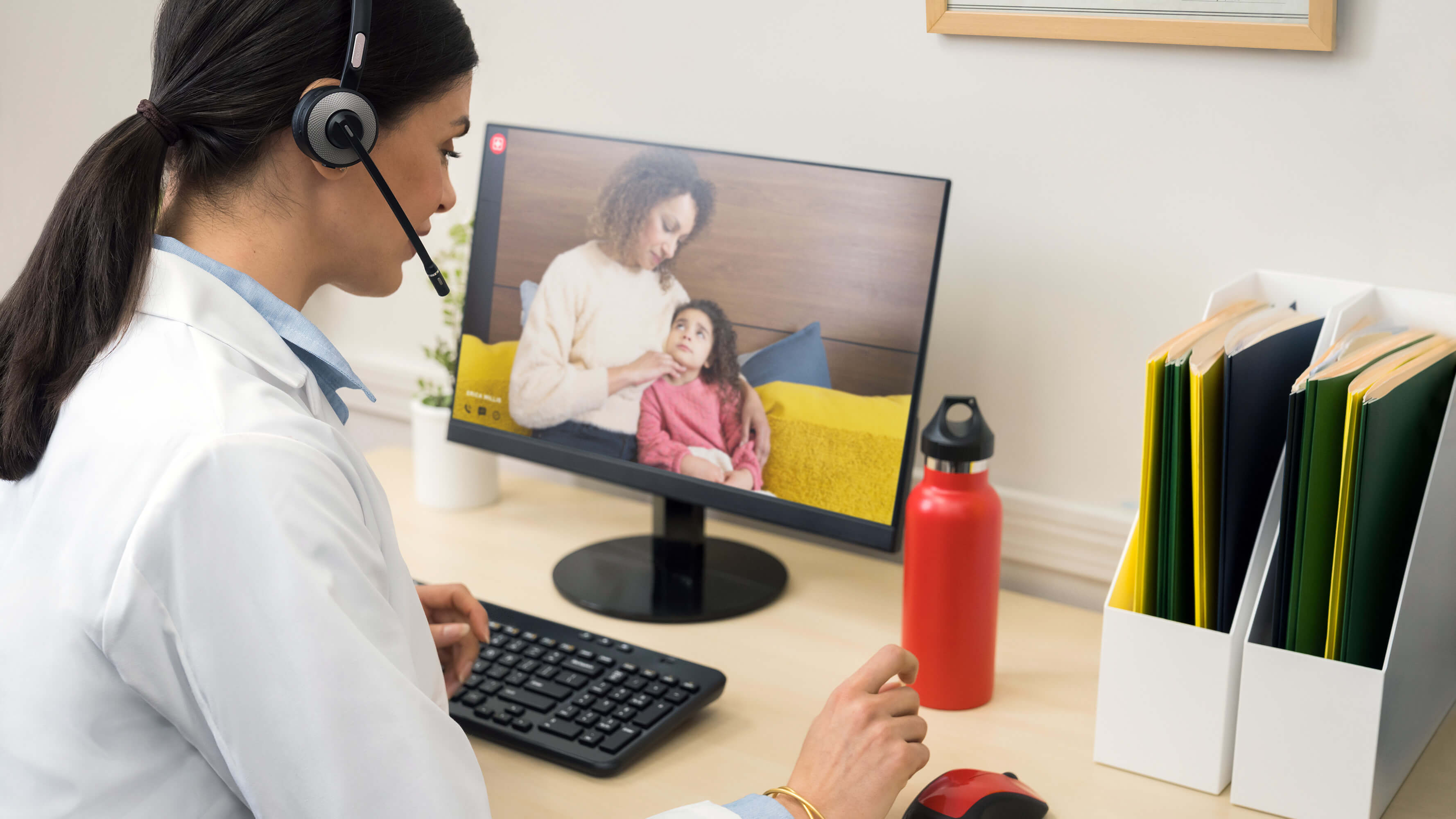A practitioner consults a female adult patient with a child via video call during a telemedicine visit.