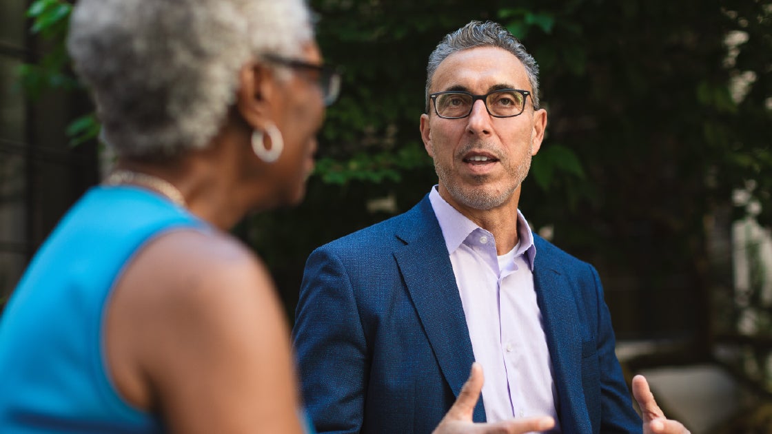 Dr. Robert Mirsky, Chief Medical Officer, Aetna, talking with an older woman outdoors.