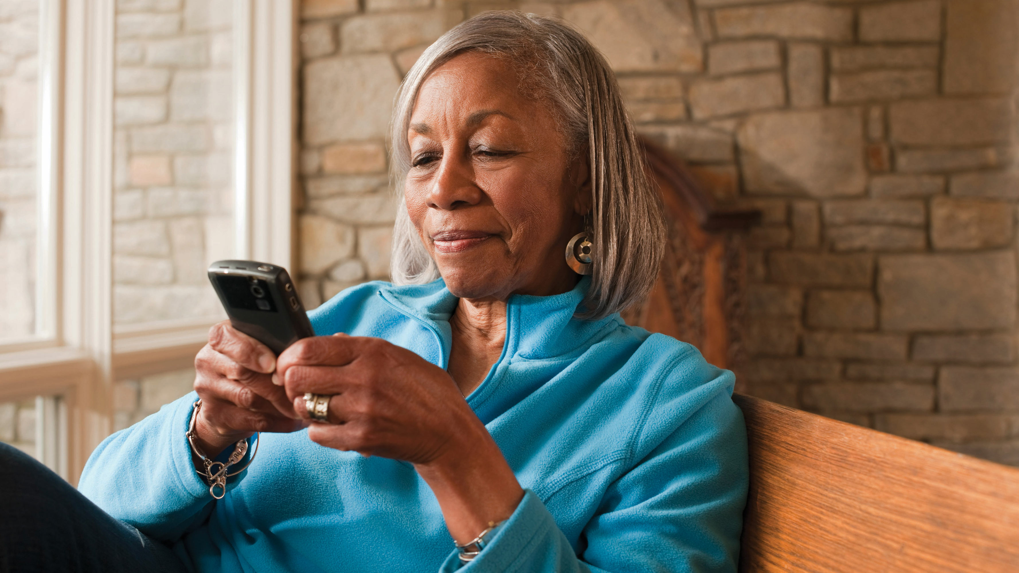 A mature woman uses a smartphone to read materials about health care.