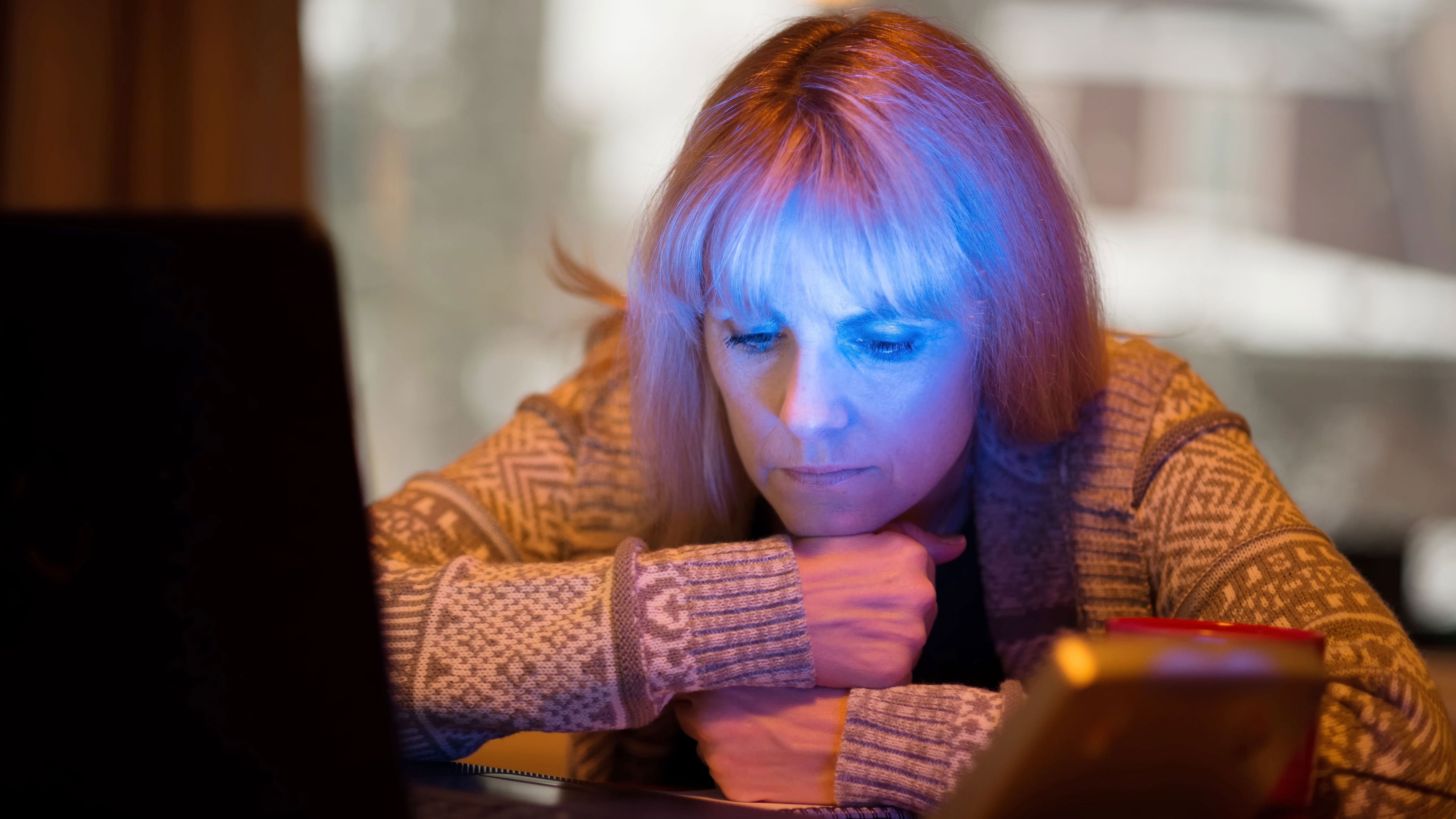 A middle aged woman sitting in front of a blue light to treat seasonal affective disorder