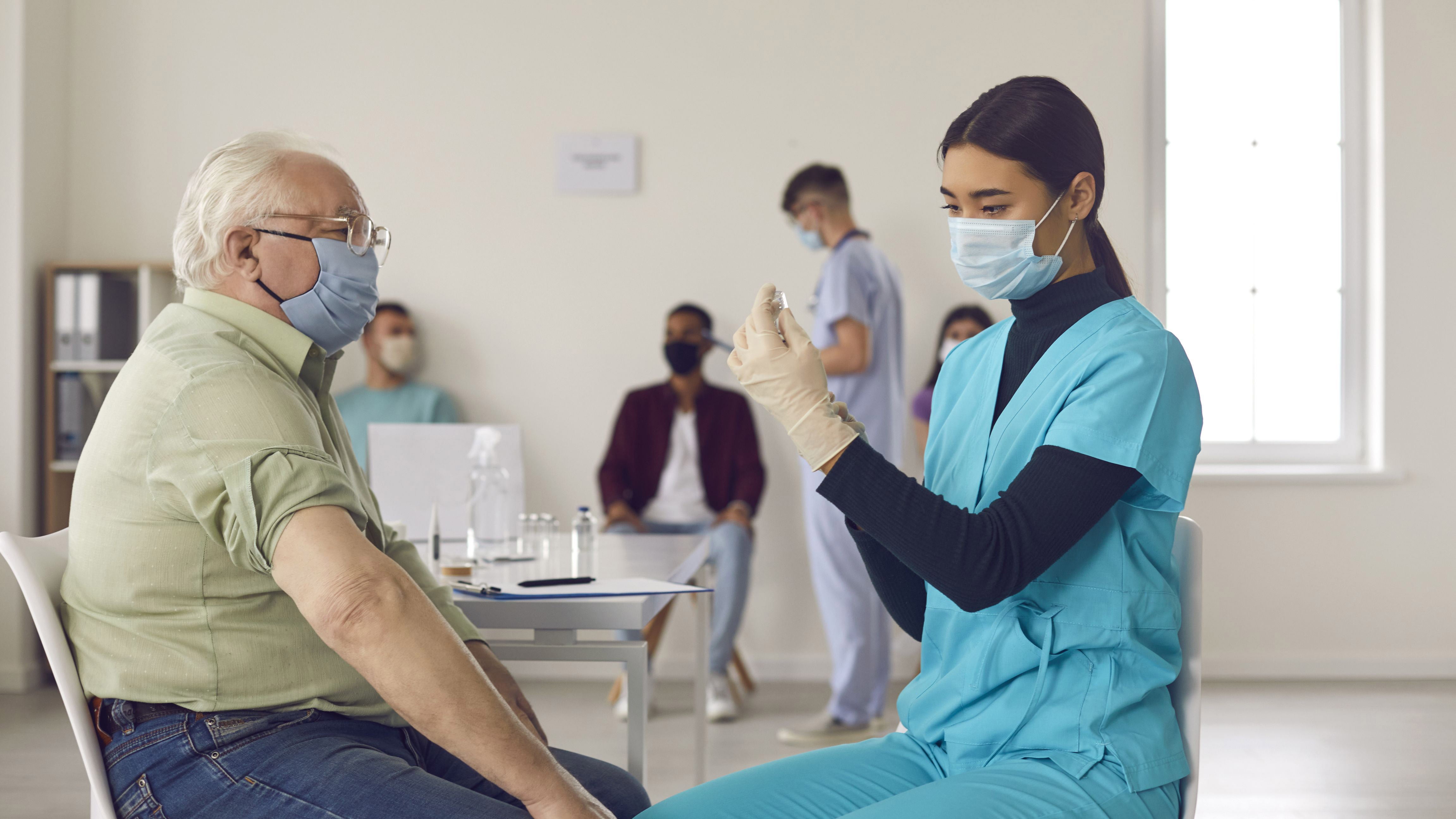 A senior man about to get a vaccination from a long-term care nurse.