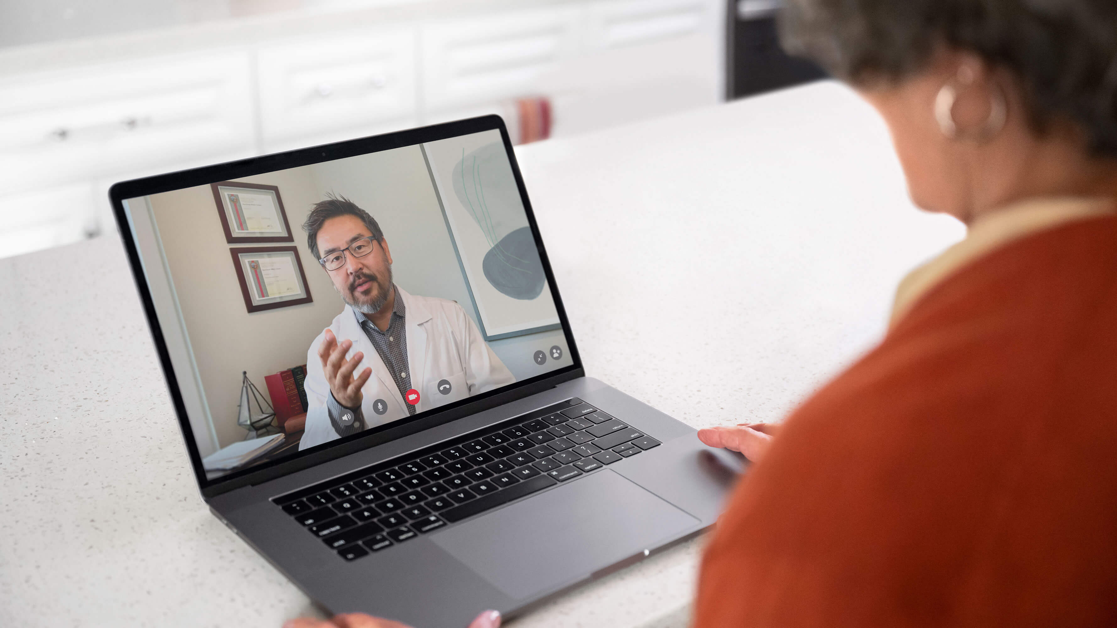 A middle aged woman talking with a doctor on her laptop in a virtual health visit.