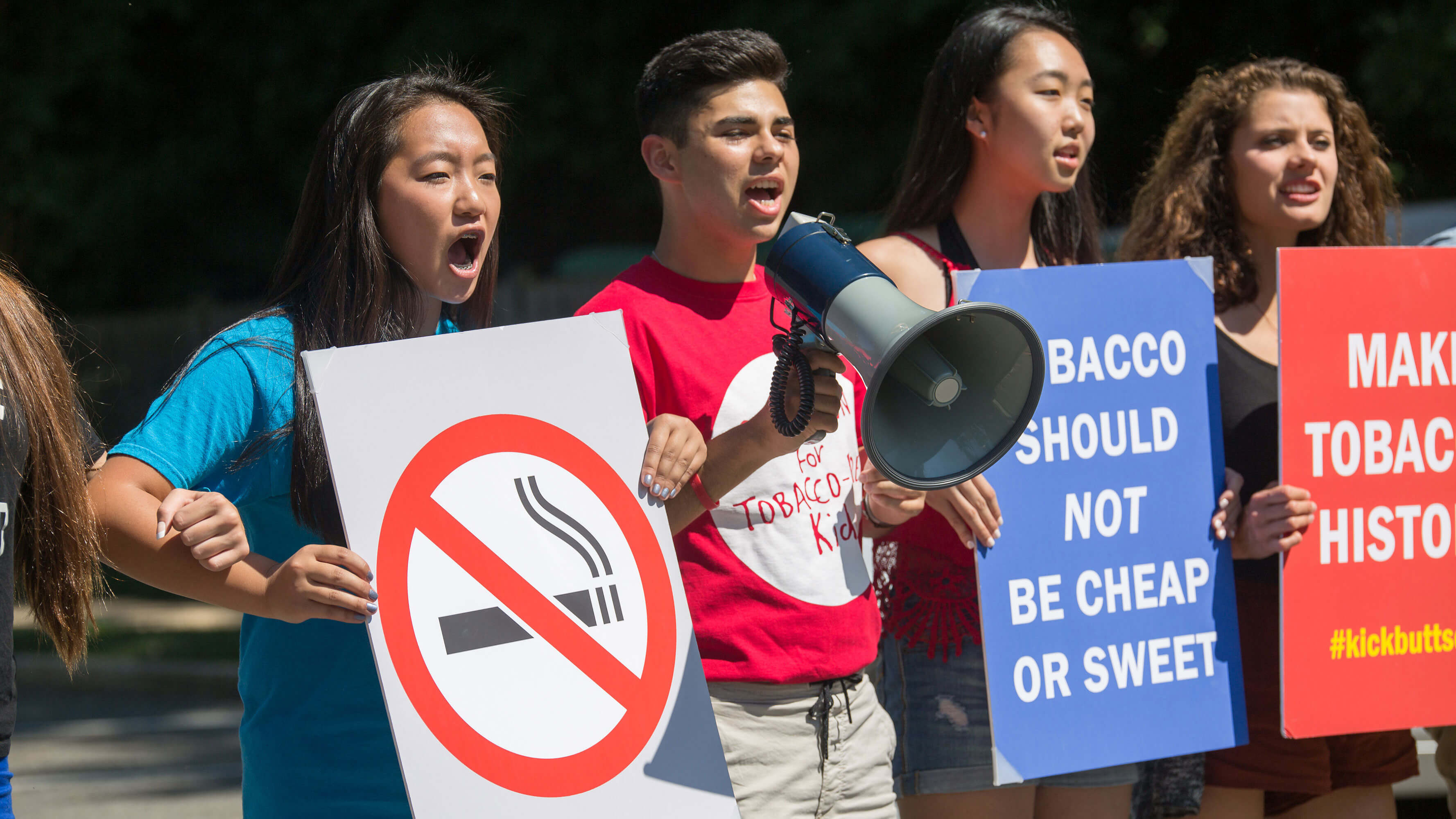 Young people standing together holding anti-tobacco signs in protest.