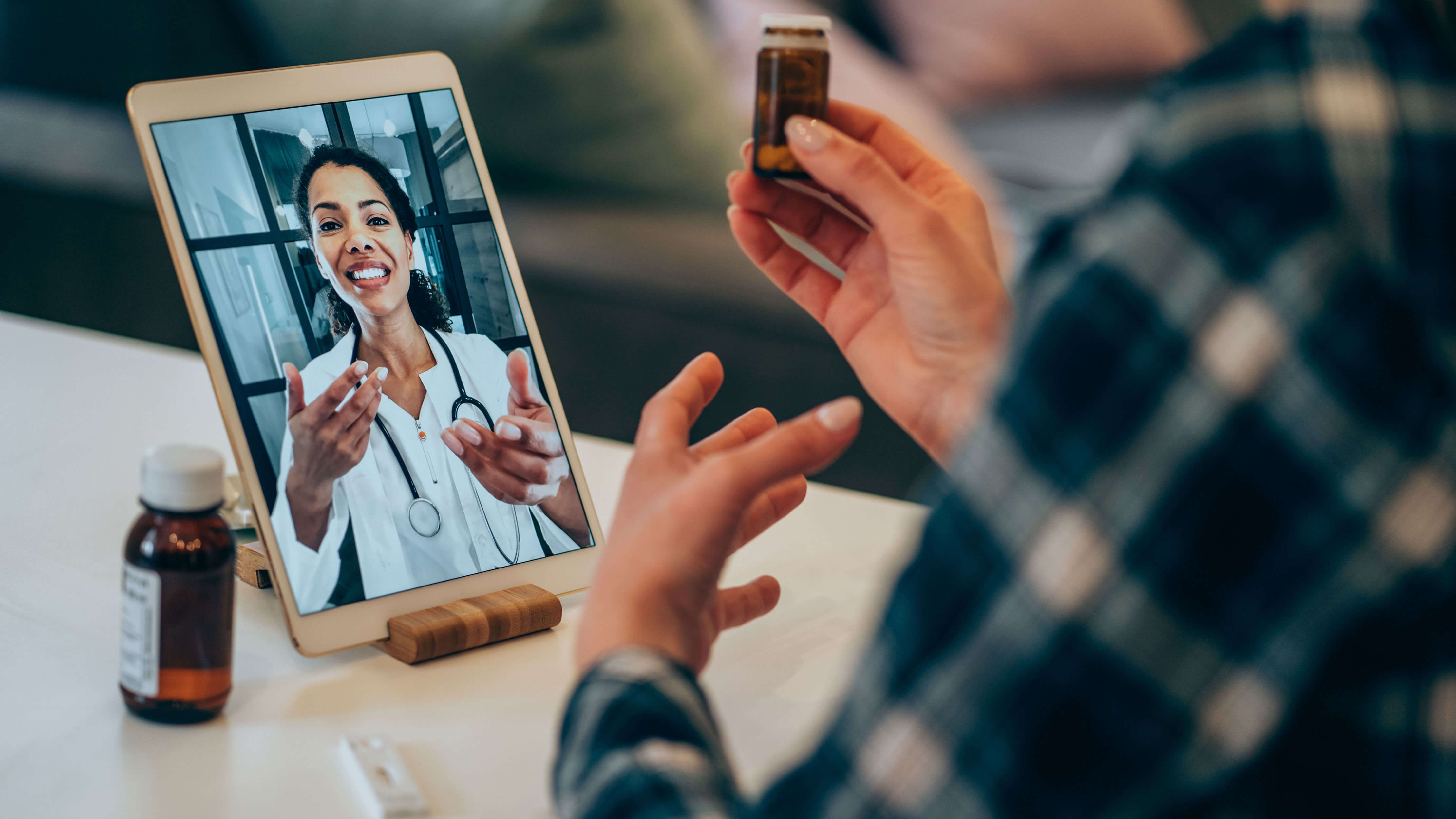 A patient holds their prescription while speaking with their doctor on a video chat via tablet. 