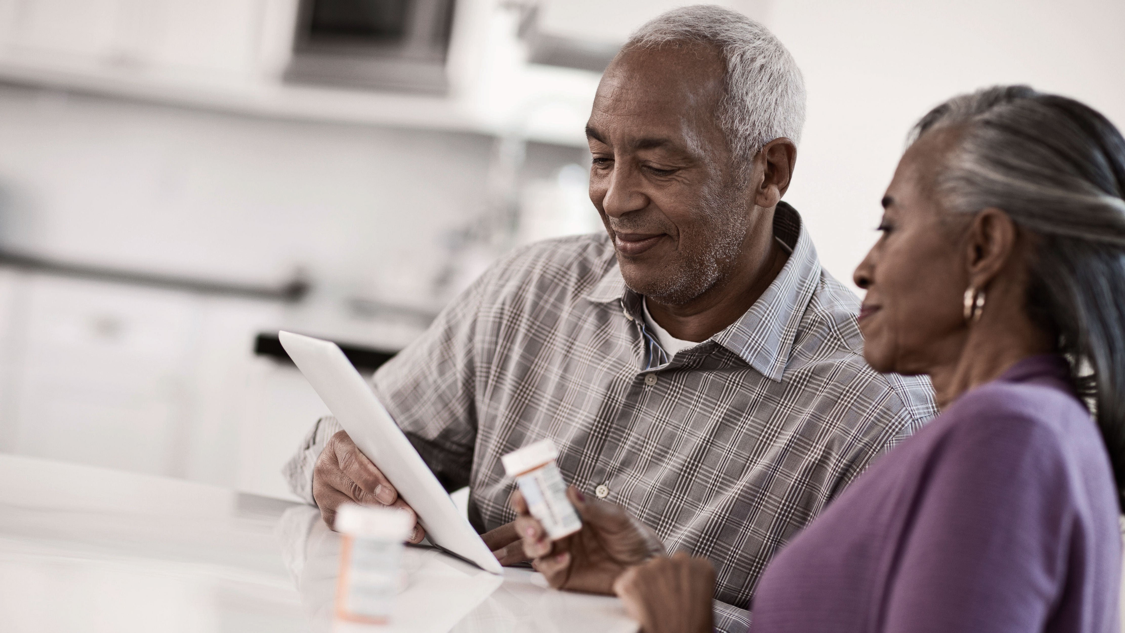 A man and woman review their medication information online using their tablet