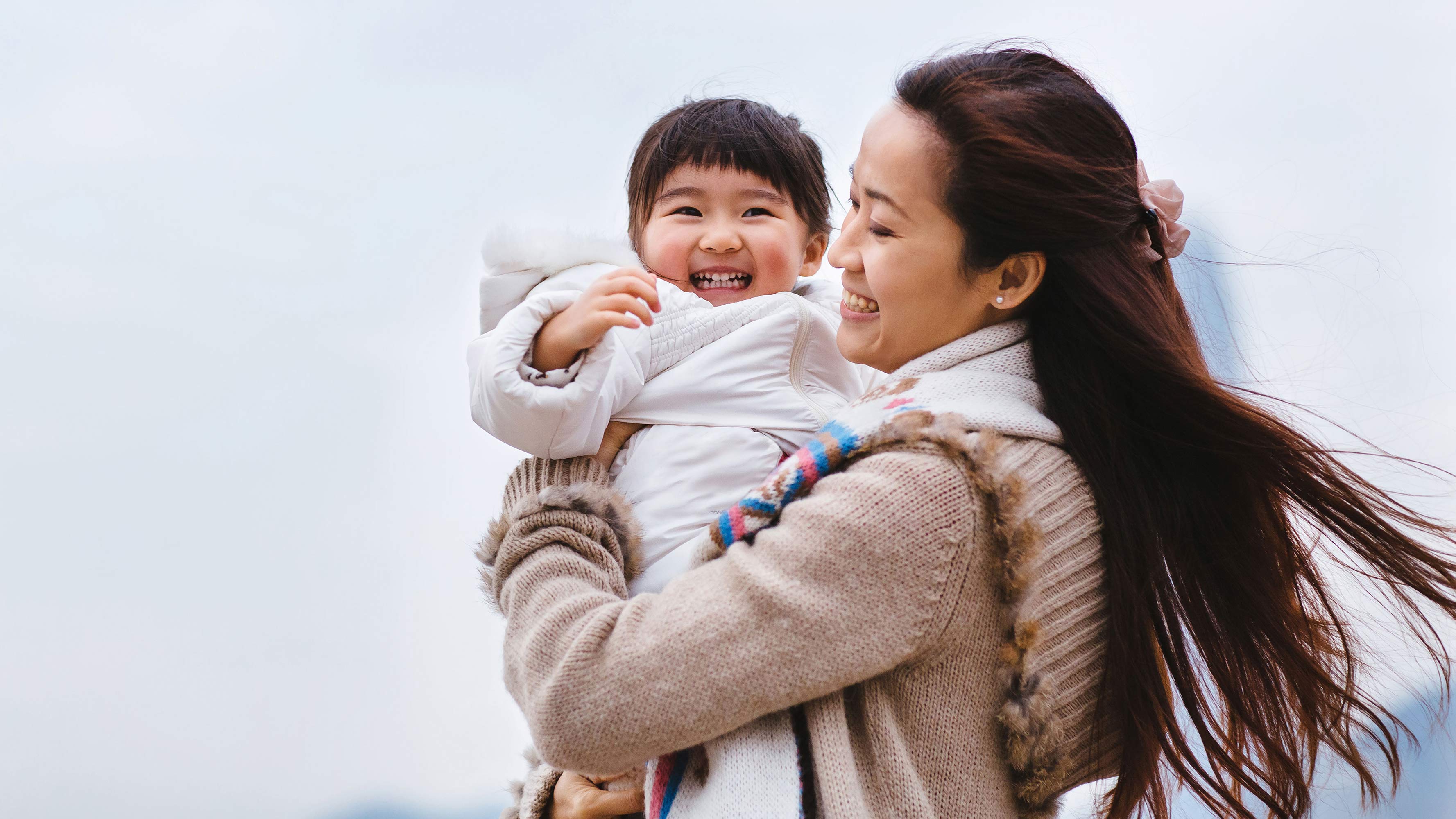 A mother, holding her infant daughter, smile and enjoy an outdoor adventure.