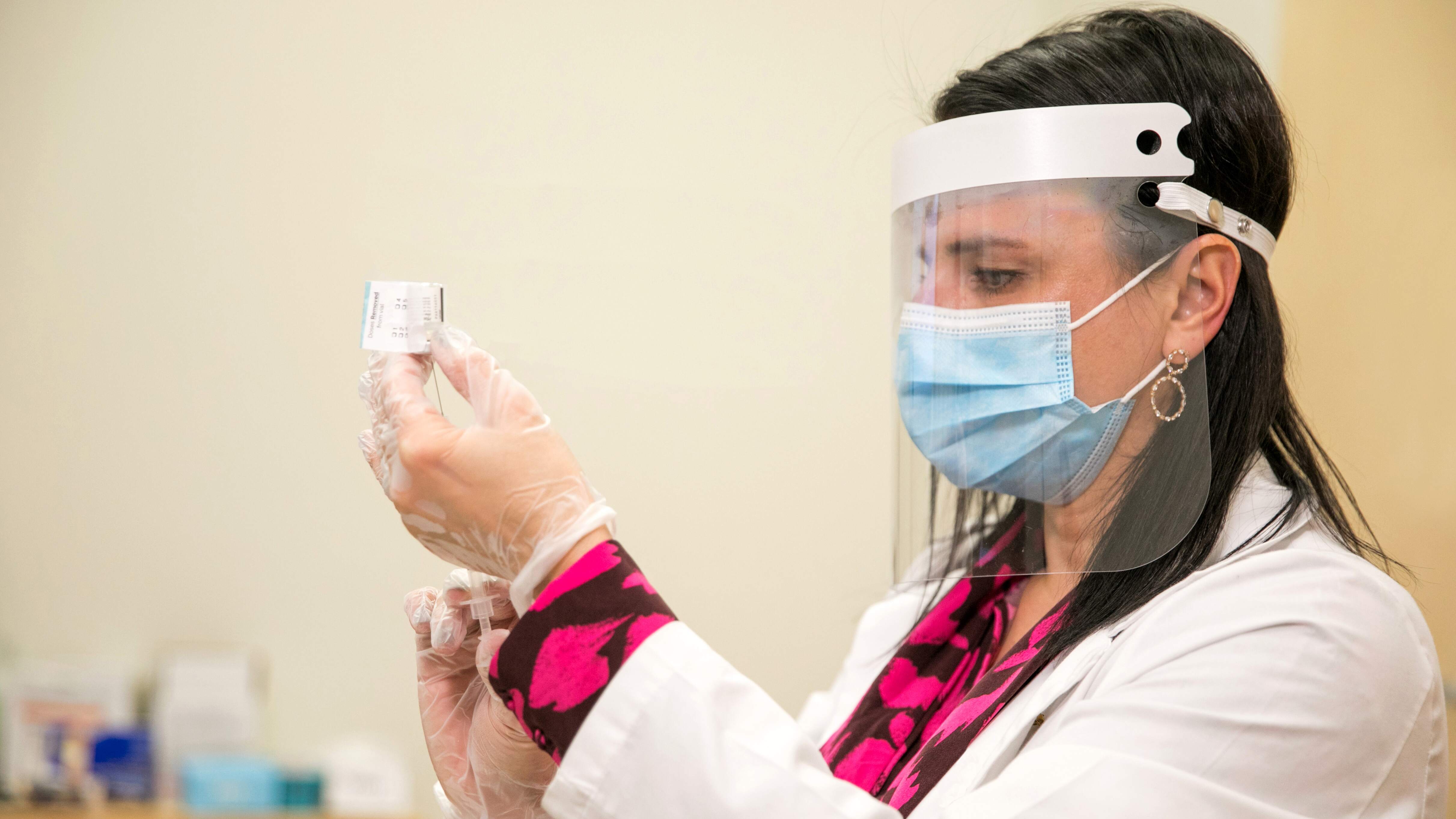 A CVS nurse, wearing PPE, draws a dose of the COVID-19 vaccine. 