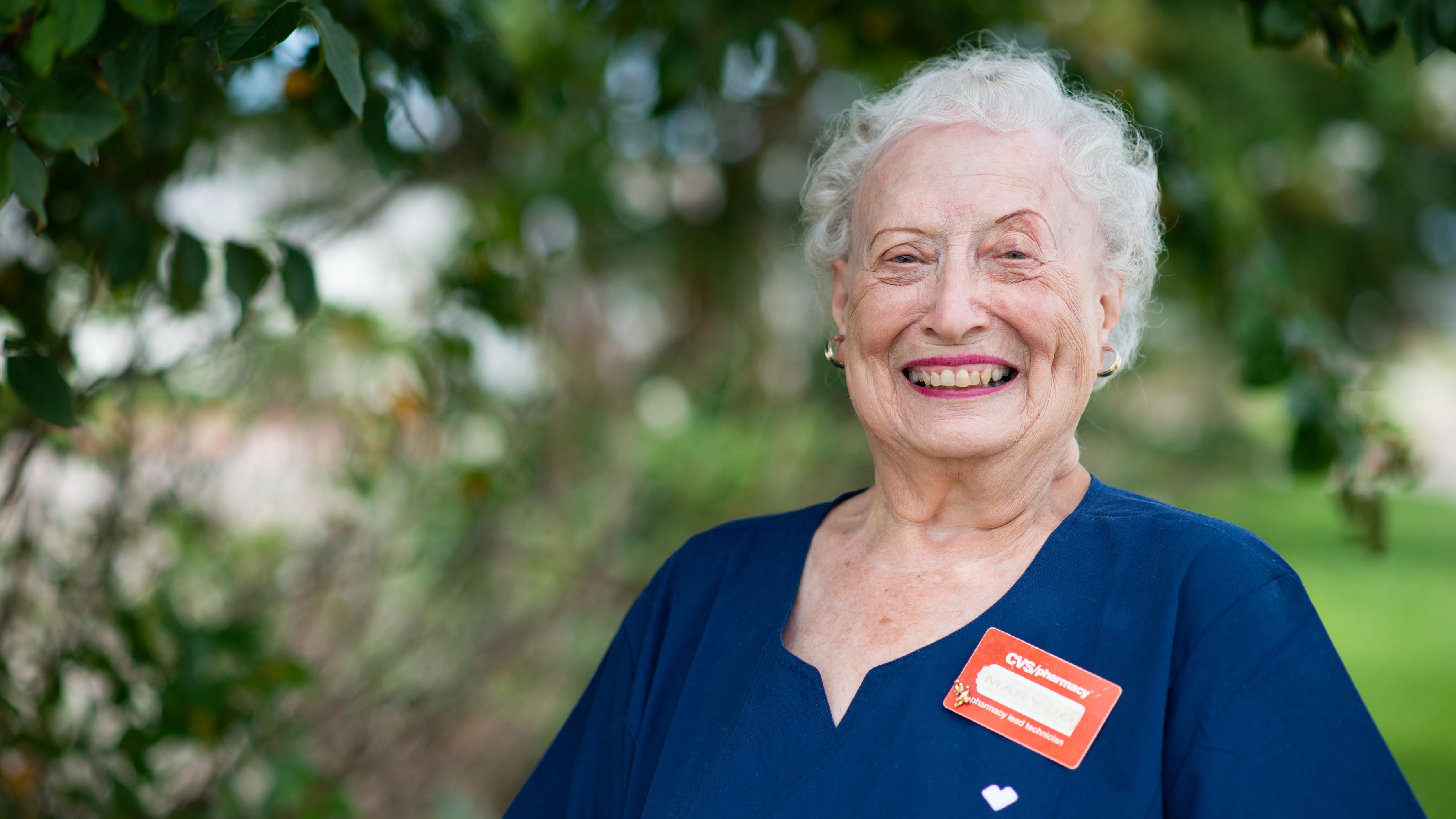 Mary Jo Nolen smiles at the camera wearing a blue CVS shirt and a red name tag.