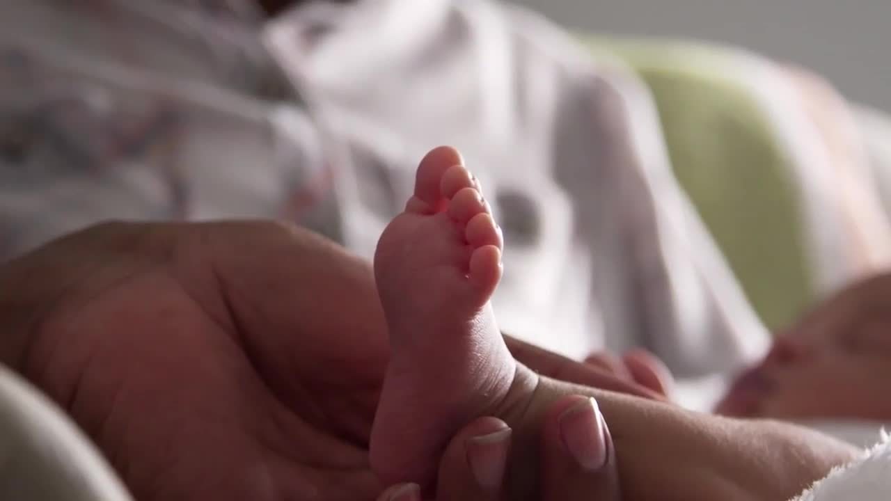 A new father tenderly holds the foot of his newborn child.