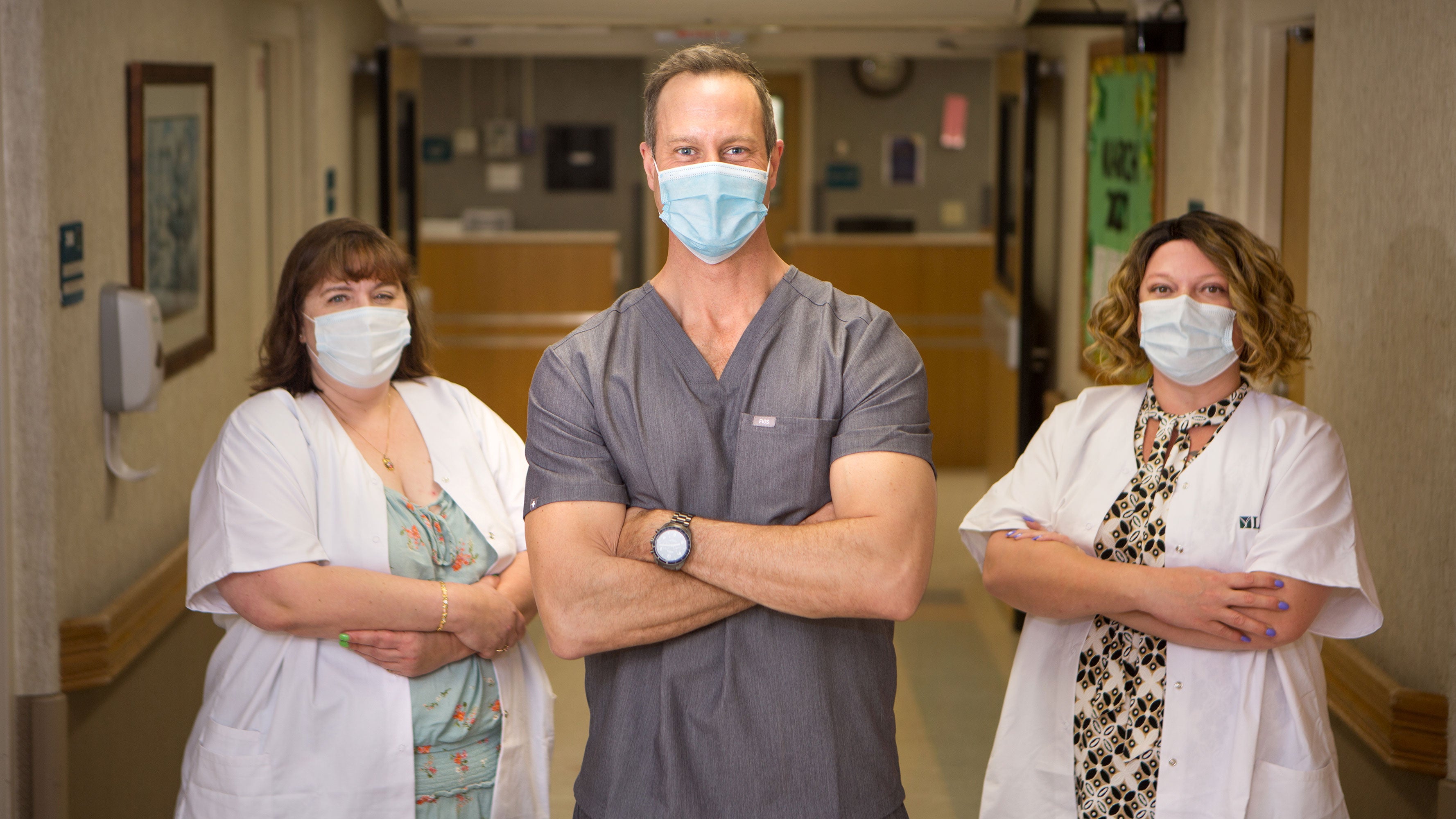 David Kirkwood stands with his arms crossed to pose for a picture with two coworkers.