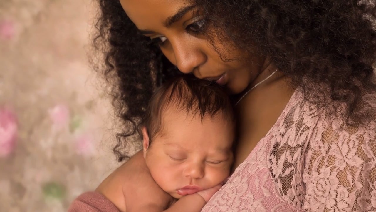 A mother holding her newborn against her chest kisses the top of the infant&#039;s head.
