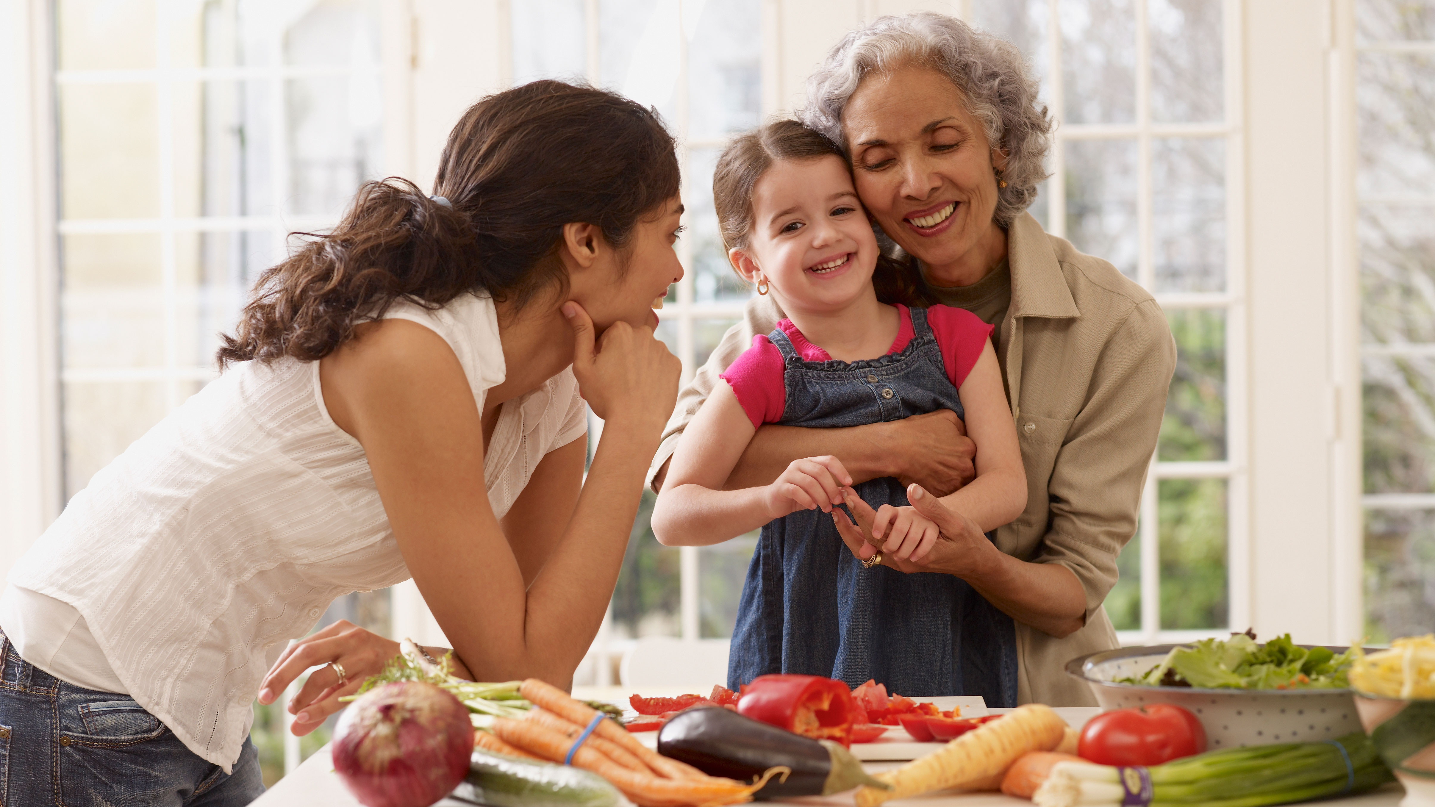 A grandmother with her daughter and granddaughter conversing at a kitchen counter
