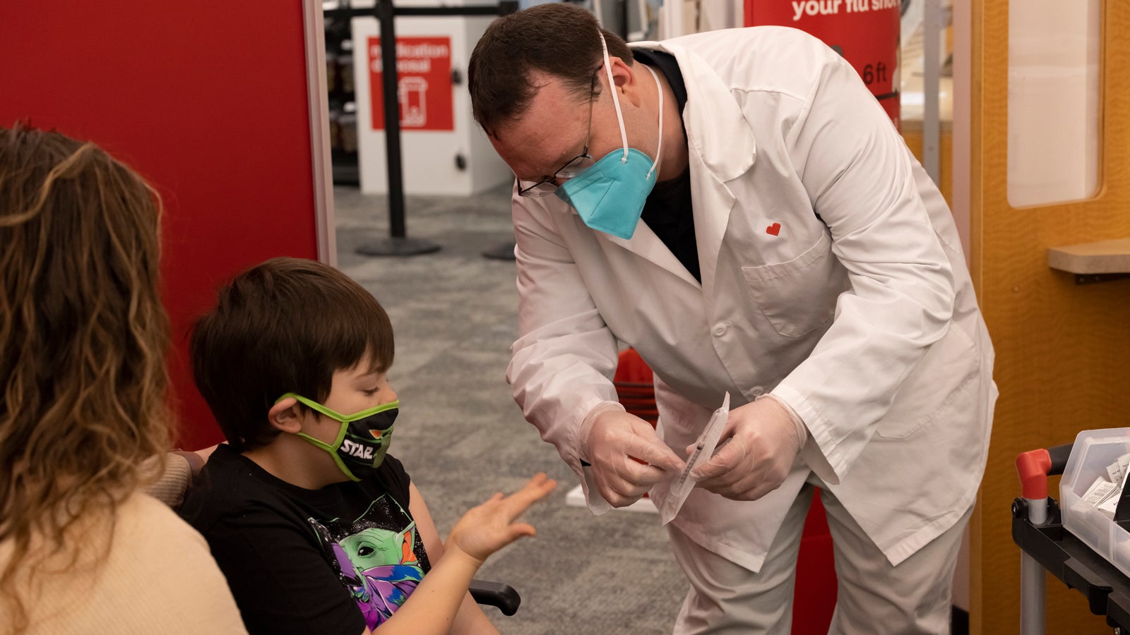 Richie and his mom talk to a healthcare provider who is pointing to a COVID-19 vaccine package.