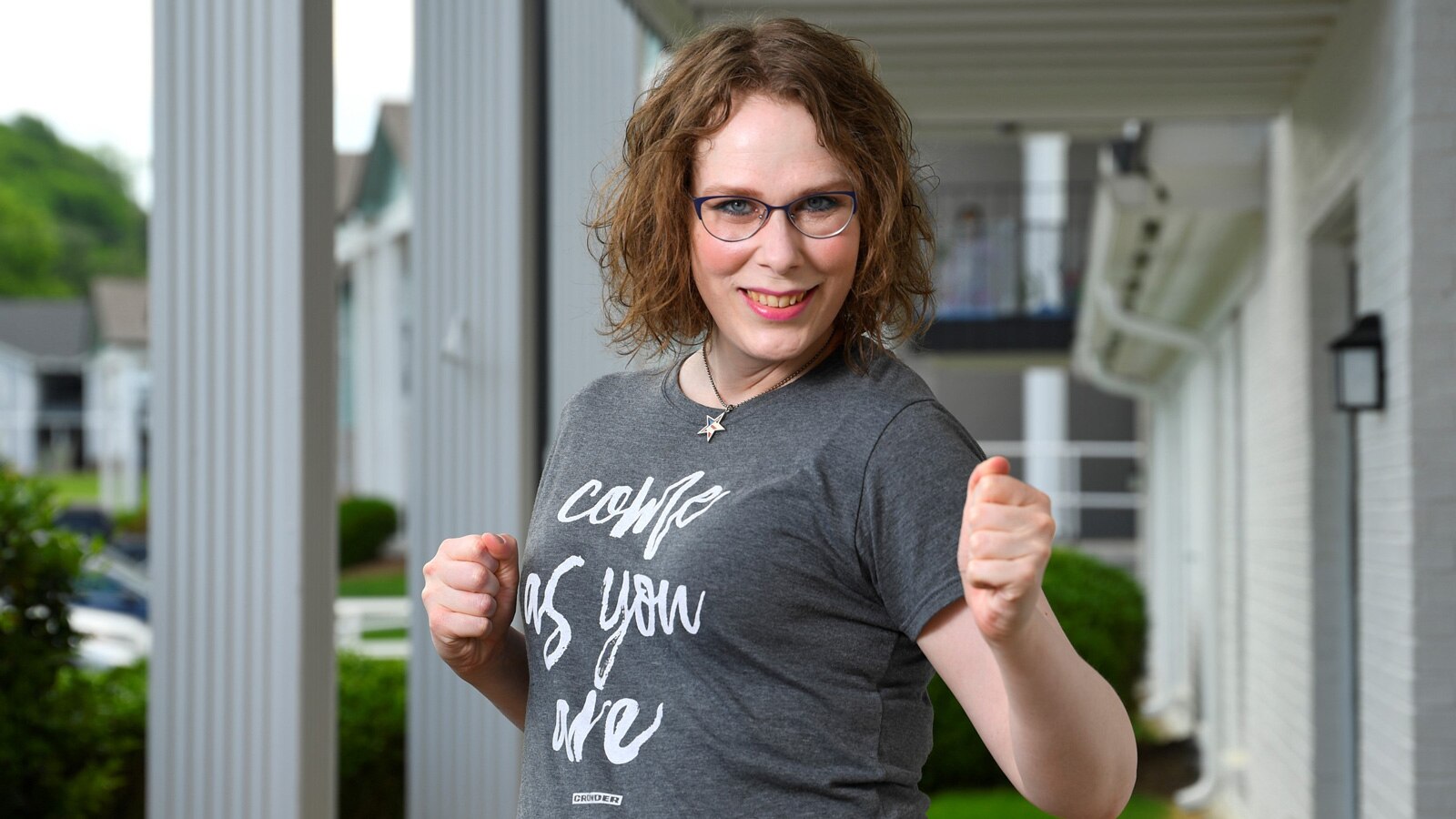 Melissa Price wears a shirt that reads “Come as you are” and she strikes a playful, empowered pose.