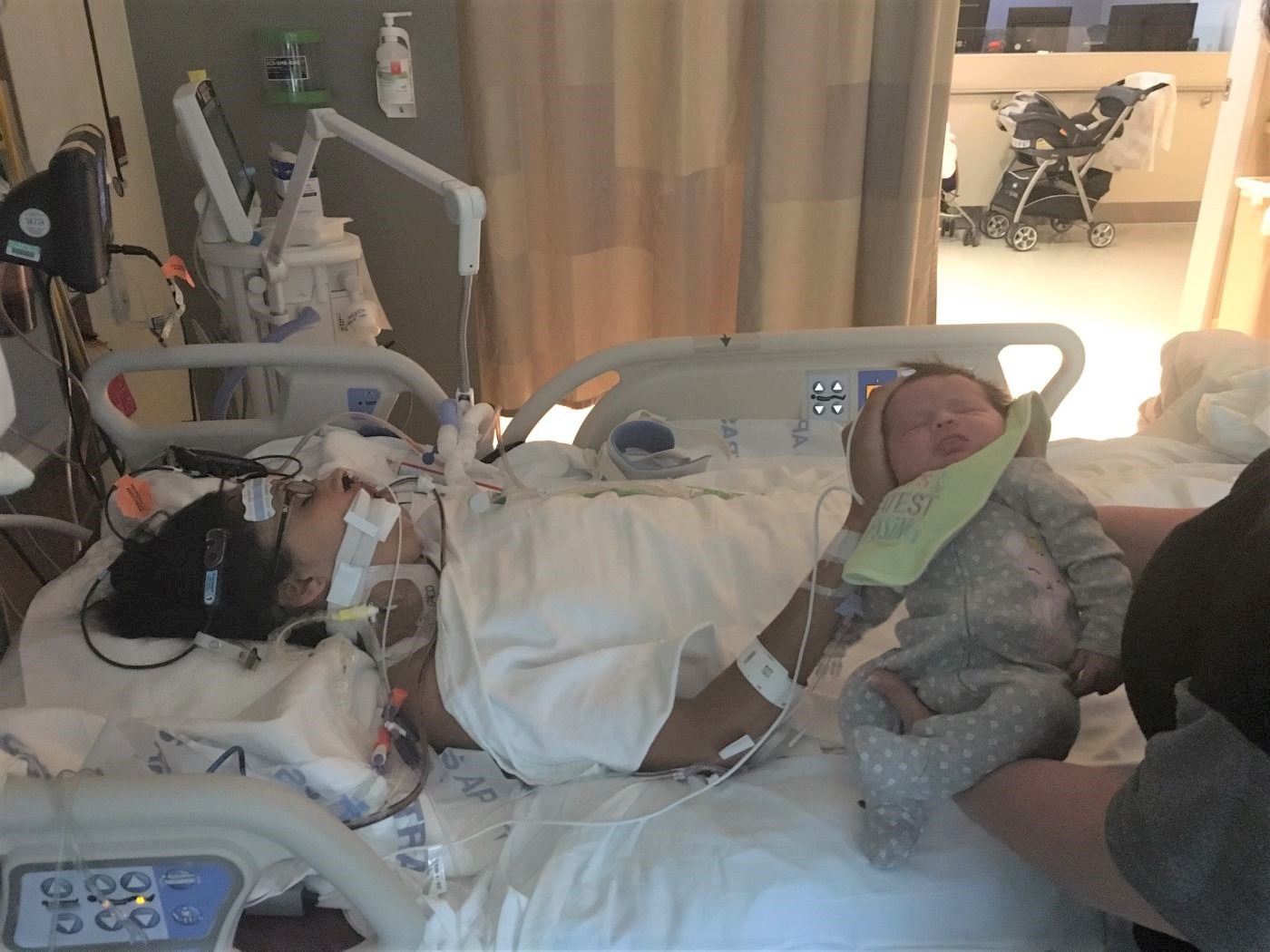 Jen Rohe in a hospital bed hooked up to machines reaches out to caress her baby.