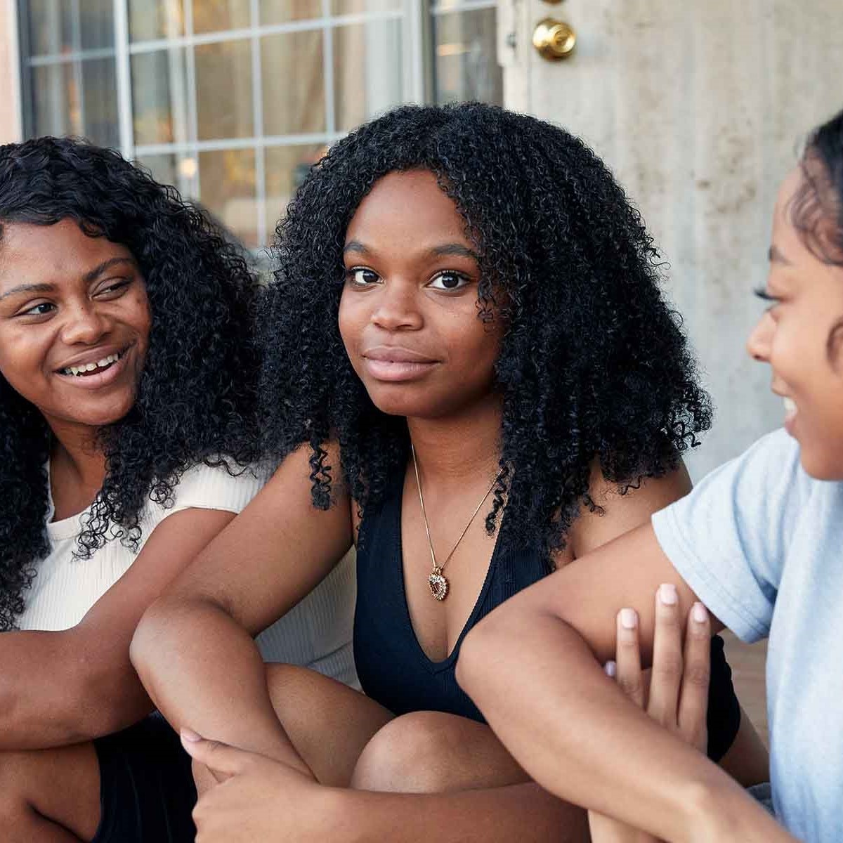Three young females sitting together on a front porch stairway