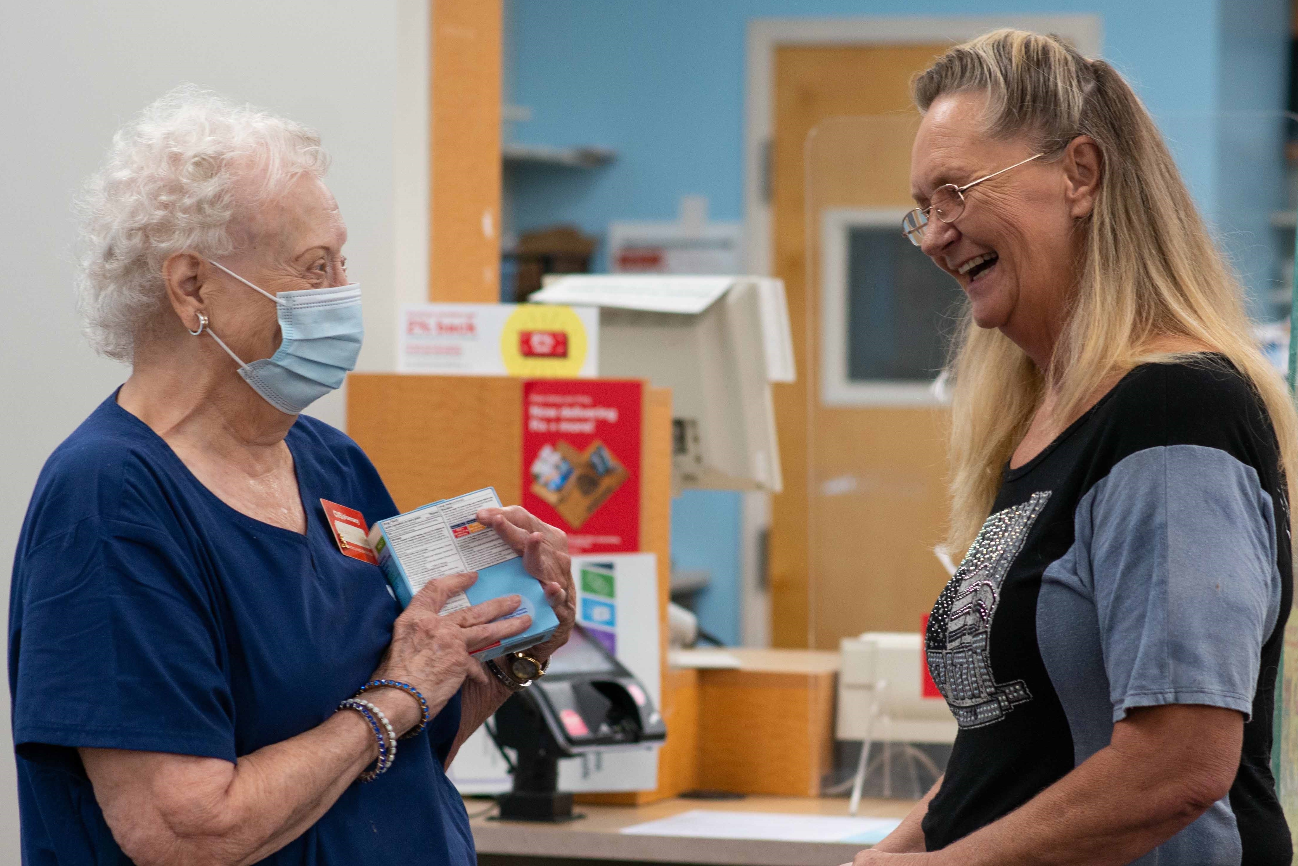 Mary Nolen, a long-time CVS Pharmacy employee wears a mask while assisting a customer