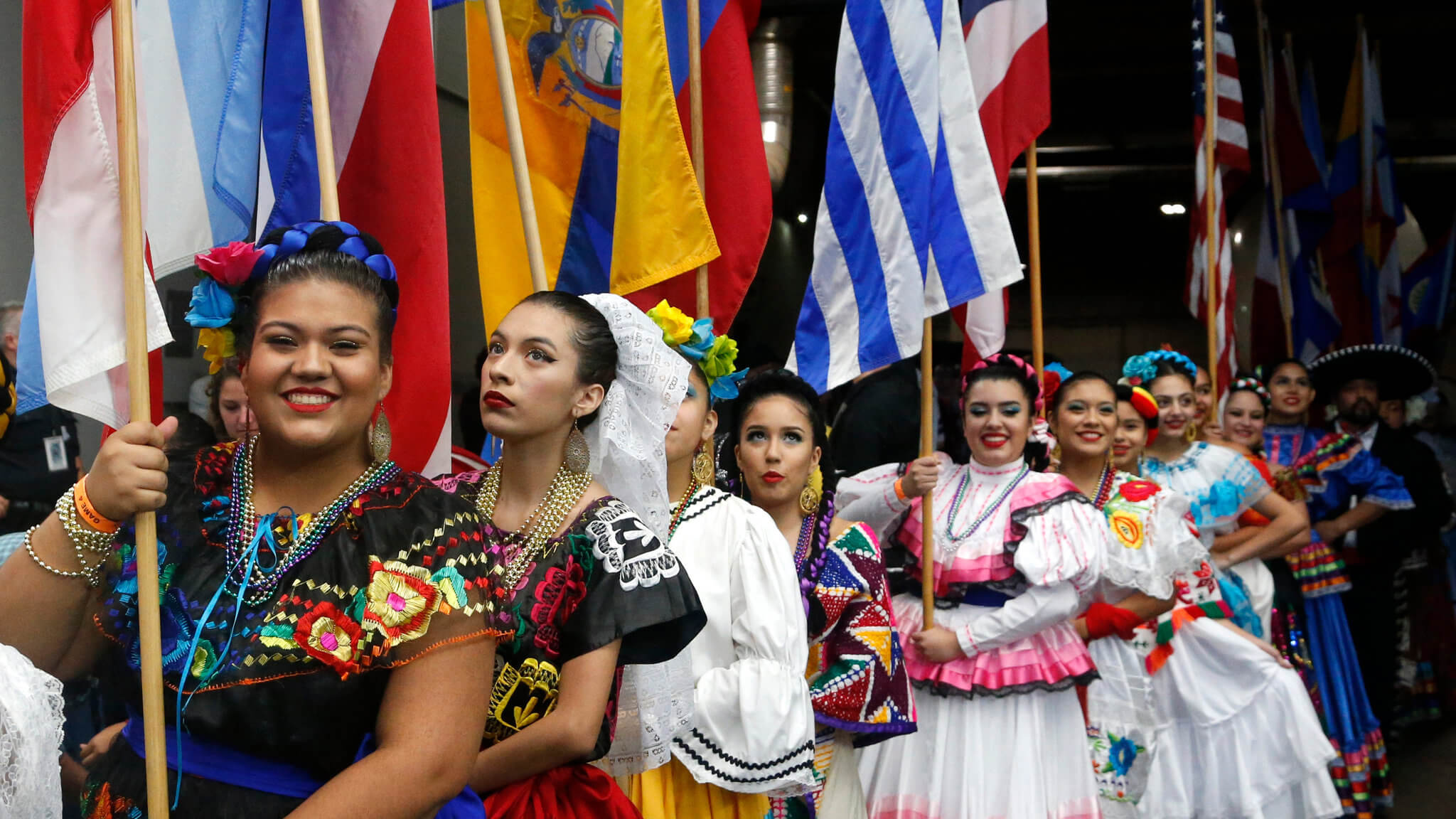 A parade of Hispanic women dressed in their traditional clothing and holding their country flags