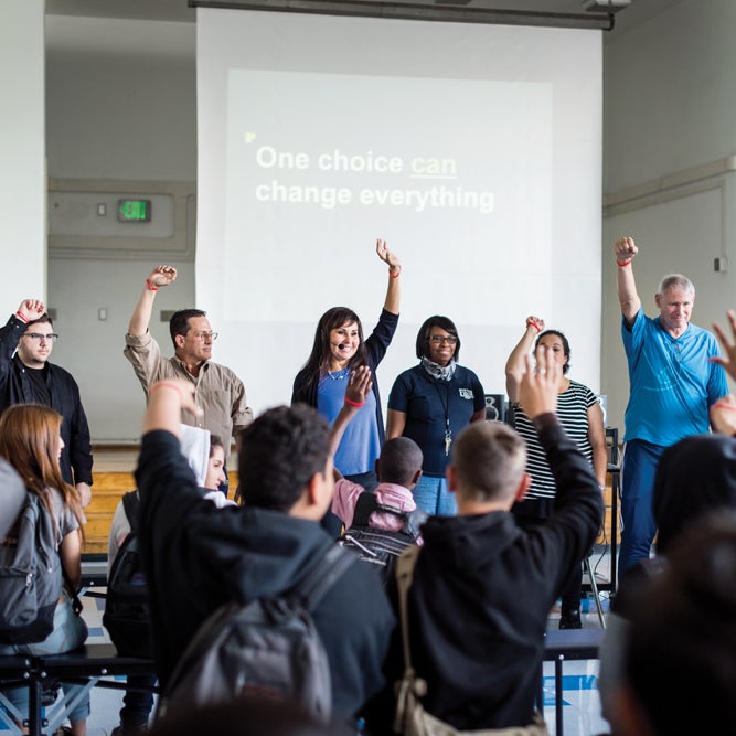 An instructor, part of the CVS Health “Pharmacists Teach” program, leads a presentation at an unknown school.